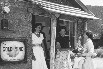 black and white photo of three women standing in front of the original Gold Mine Thrift Store.