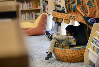 child reading at the base of the totem pole in the Children's Library
