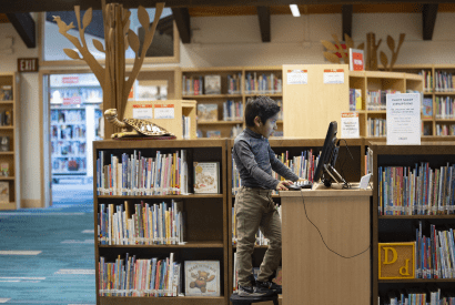 A child searching for a book on one of the PACs in the Children's Library