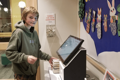 A tween uses the self-checkout station in the Children's library