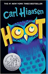 Book Cover, Hoot by Carl Hiaasen. Blue Owl with HOOT in yellow, Newbery Honor sticker