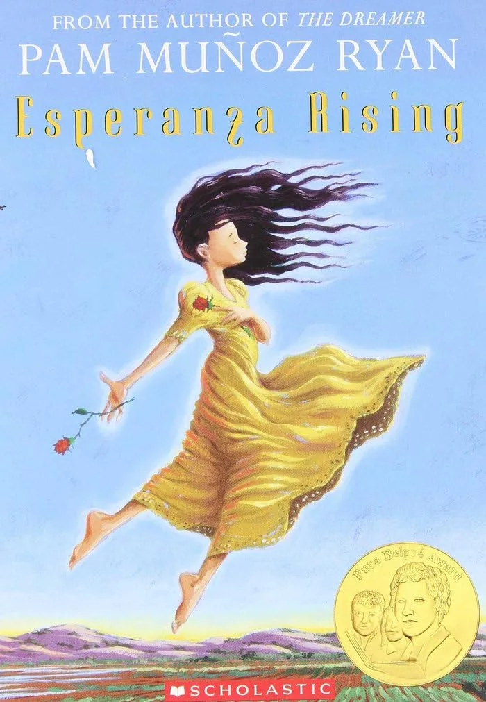 Girl in yellow dress and dark hair whipping forward in the wind floating over farm fields with red roses in each hand