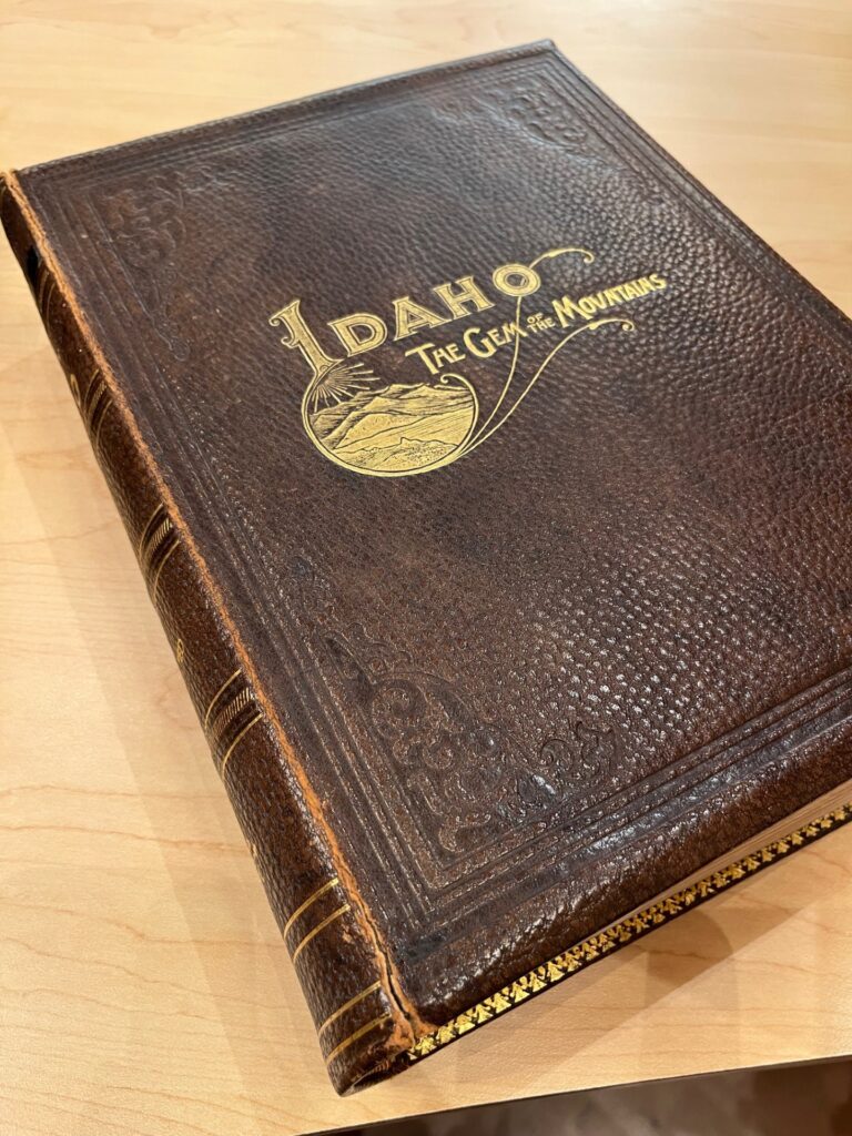 Leatherbound book with gold embossing, cover reads "Idaho The Gem of the Mountains"