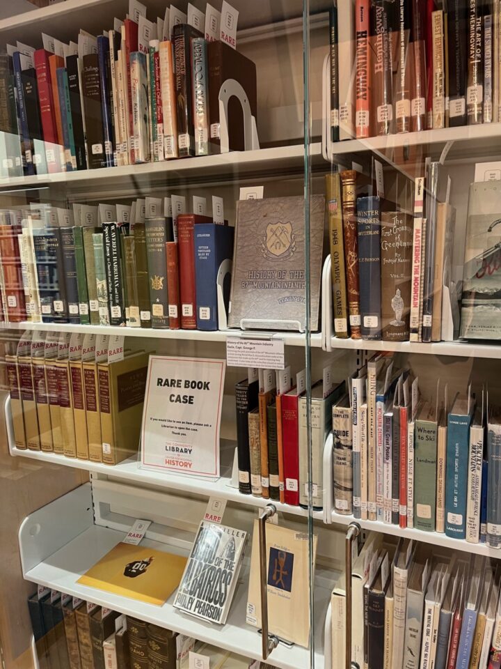 A book shelf with glass door in front of it.