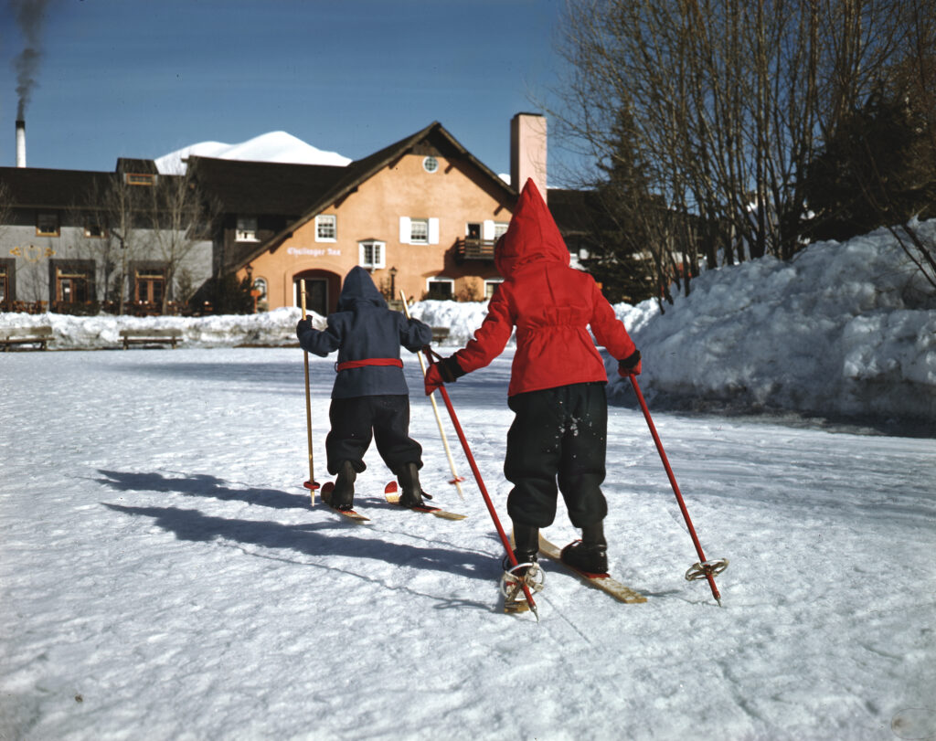 Two kids ski towards the Challenger Inn